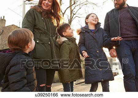 Stock Photograph - Mid adult couple and three children strolling on street. Fotosearch