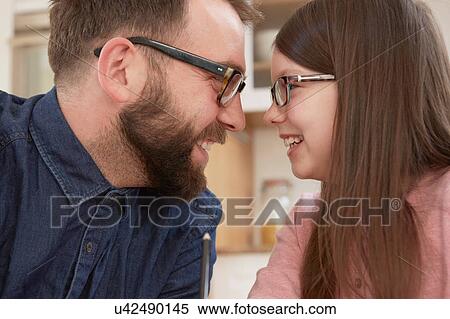 Stock Photography - Mid adult man and daughter smiling face to face. Fotosearch