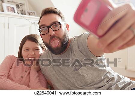 Mid adult man and daughter taking smartphone selfie View Large Photo Image Stock Image - Mid adult man and daughter taking smartphone selfie. Fotosearch