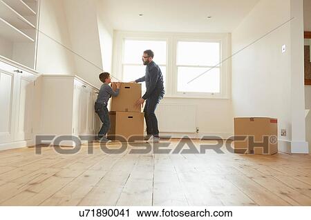 Stock Image - Mid adult man and son stacking cardboard box in new home. Fotosearch