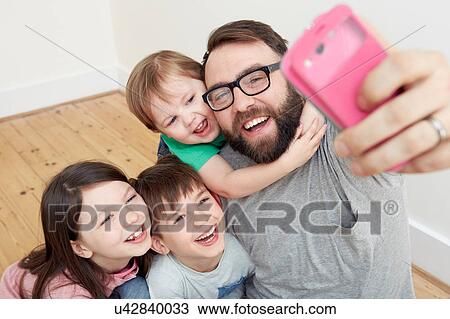 Mid adult man and three children taking smartphone selfie View Large Photo Image Stock Image - Mid adult man and three children taking smartphone selfie. Fotosearch