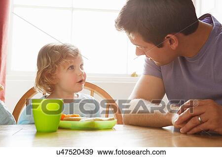 Stock Photo - Mid adult man and toddler daughter at kitchen table. Fotosearch
