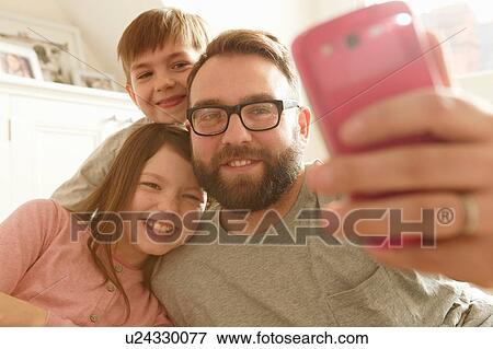 Mid adult man and two children taking smartphone selfie View Large Photo Image Stock Photo - Mid adult man and two children taking smartphone selfie. Fotosearch