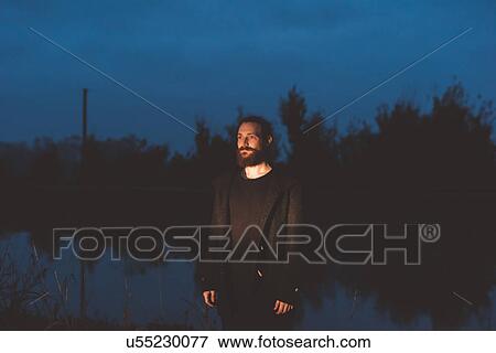 Mid adult man on canal waterfront at night View Large Photo Image Stock Photo - Mid adult man on canal waterfront at night. Fotosearch