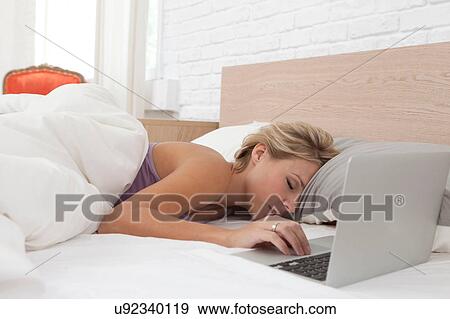 Mid adult woman asleep in bed by laptop View Large Photo Image Stock Photo - Mid adult woman asleep in bed by laptop. Fotosearch
