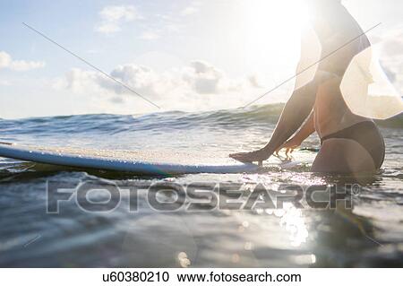 Stock Image - Mid section of woman with surfboard in sea, Nosara, Guanacaste Province, Costa Rica. Fotosearch