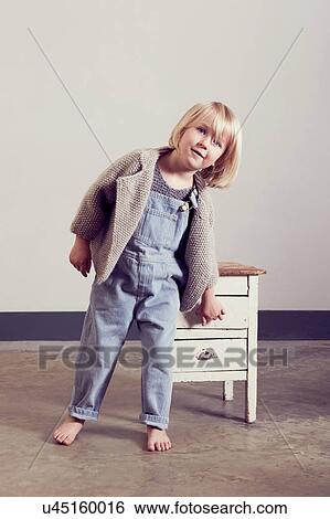 Stock Photograph - Mischievous girl opening drawer of old cabinet. Fotosearch