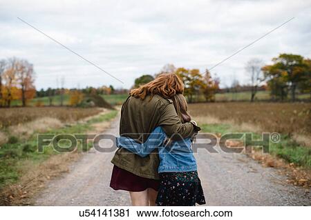 Stock Image - Mother and daughter hugging on dirt road, Lakefield, Ontario, Canada. Fotosearch