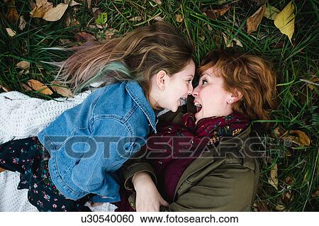 Mother and daughter lying on grass making funny faces View Large Photo Image Stock Image - Mother and daughter lying on grass making funny faces. Fotosearch