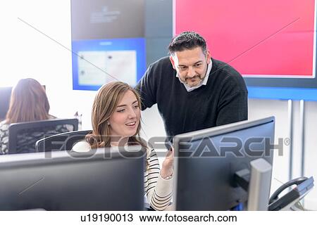 Stock Image - Office workers directing social media in call centre in car factory. Fotosearch