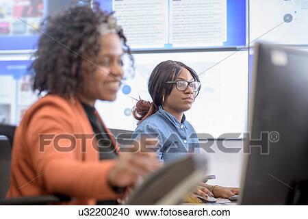 Stock Image - Office workers directing social media in call centre in car factory. Fotosearch