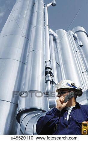 Oil refinery worker on phone with pipework View Large Photo Image Stock Image - Oil refinery worker on phone with pipework. Fotosearch