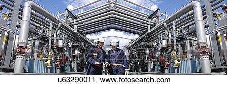 Stock Image - Oil refinery workers and pipework. Fotosearch