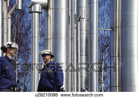 Stock Photograph - Oil refinery workers and pipework. Fotosearch
