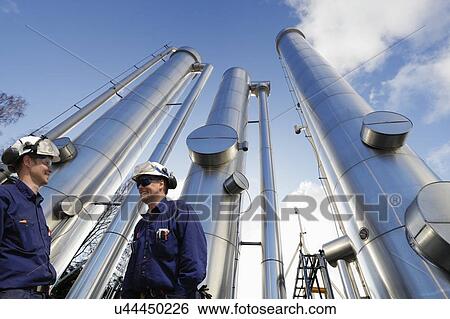 Oil refinery workers and pipework View Large Photo Image Stock Photograph - Oil refinery workers and pipework. Fotosearch
