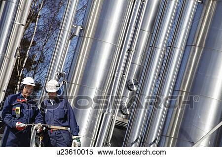 Oil refinery workers and pipework View Large Photo Image Stock Photography - Oil refinery workers and pipework. Fotosearch