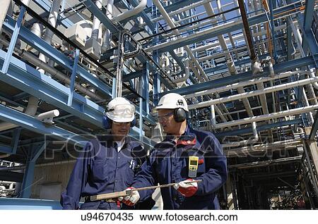 Stock Photography - Oil refinery workers and pipework. Fotosearch