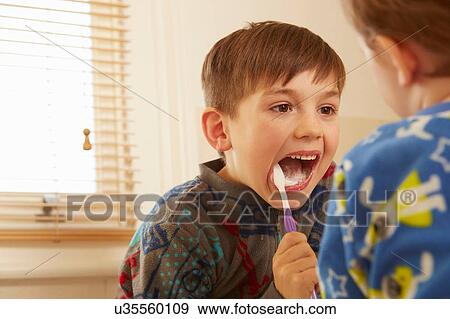 Stock Photo - Over shoulder view of boy and brother brushing teeth in bathroom. Fotosearch