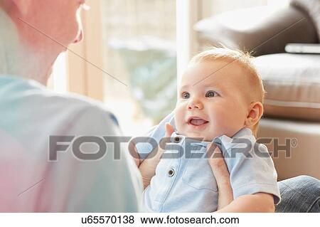 Stock Photo - Over shoulder view of mature man with baby son on his lap. Fotosearch