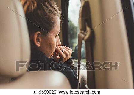 Stock Image - Over shoulder view of woman in car looking through window. Fotosearch
