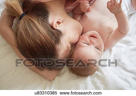 Overhead view of woman on bed kissing baby son on cheek View Large Photo Image Stock Photography - Overhead view of woman on bed kissing baby son on cheek. Fotosearch