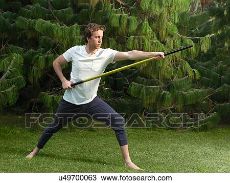 Poised young man in park practicing martial arts holding bo staff View Large Photo Image Stock Image - Poised young man in park practicing martial arts holding bo staff. Fotosearch