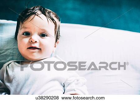 Stock Photo - Portrait of baby boy lying in bed. Fotosearch
