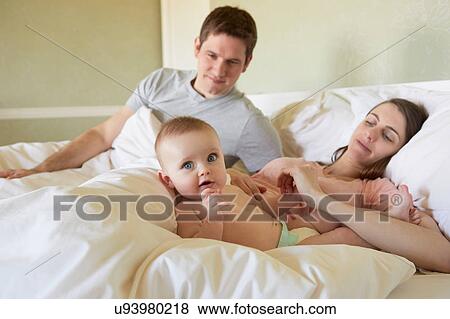 Portrait of baby girl lying on bed with parents View Large Photo Image Stock Photo - Portrait of baby girl lying on bed with parents. Fotosearch