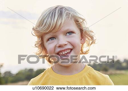 Stock Image - Portrait of blond-haired, blue-eyed boy on playing field. Fotosearch