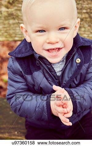 Portrait of blue eyed male toddler on park bench View Large Photo Image Stock Photo - Portrait of blue eyed male toddler on park bench. Fotosearch