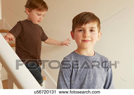 Stock Image - Portrait of boy and toddler brother on stairs. Fotosearch