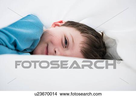 Portrait of boy lying between white bed sheets View Large Photo Image Picture - Portrait of boy lying between white bed sheets. Fotosearch