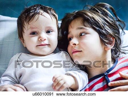 Portrait of boy lying in bed looking sideways at baby brother View Large Photo Image Stock Image - Portrait of boy lying in bed looking sideways at baby brother. Fotosearch