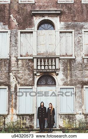 Stock Image - Portrait of couple standing at doorway of old house. Fotosearch