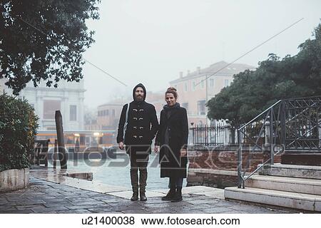 Portrait of couple standing by misty canal, Venice, Italy View Large Photo Image Stock Photo - Portrait of couple standing by misty canal, Venice, Italy. Fotosearch