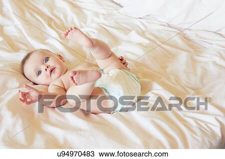 Portrait of cute blue eyed baby girl in diaper lying on bed View Large Photo Image Stock Image - Portrait of cute blue eyed baby girl in diaper lying on bed. Fotosearch