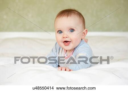 Portrait of cute blue eyed baby girl lying on bed View Large Photo Image Picture - Portrait of cute blue eyed baby girl lying on bed. Fotosearch