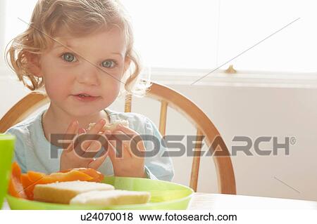 Portrait of cute blue eyed female toddler at kitchen table View Large Photo Image Stock Photo - Portrait of cute blue eyed female toddler at kitchen table. Fotosearch