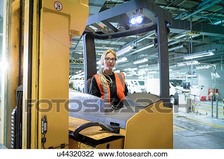 Stock Image - Portrait of female forklift driver in car factory. Fotosearch