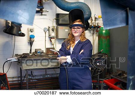 Stock Photo - Portrait of female higher education student holding welding torch in workshop at college. Fotosearch