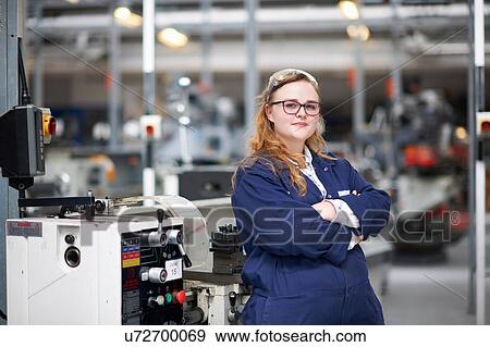 Stock Photo - Portrait of female higher education student in machine workshop at college. Fotosearch