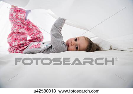 Portrait of female toddler lying between white bed sheets View Large Photo Image Stock Image - Portrait of female toddler lying between white bed sheets. Fotosearch