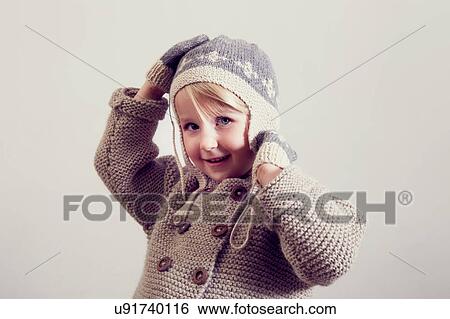 Stock Photograph - Portrait of girl adjusting hand knitted hat. Fotosearch