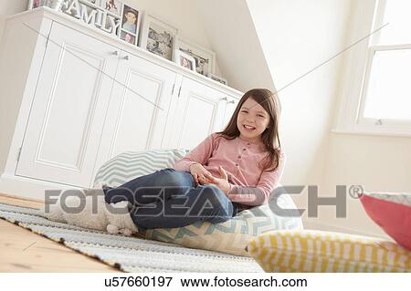 Stock Photo - Portrait of girl reclining on beanbag chair. Fotosearch