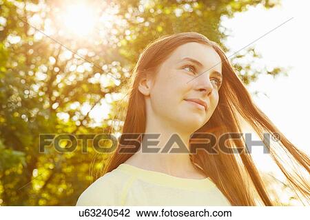 Stock Image - Portrait of girl with long brown hair in park. Fotosearch