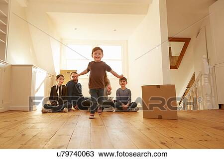 Stock Image - Portrait of male toddler and family sitting on floor in new home. Fotosearch