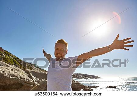 Picture - Portrait of mature man on beach, arms outstretched, Cape Town, South Africa. Fotosearch