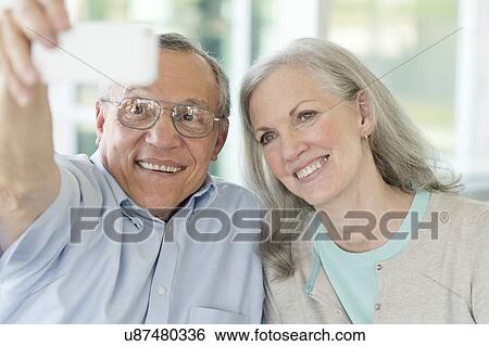 Stock Photograph - Portrait of senior couple taking selfie on phone. Fotosearch