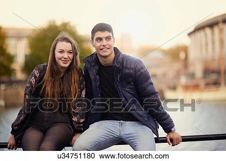 Portrait of two friends, sitting on railing by river, Bristol, UK View Large Photo Image Stock Image - Portrait of two friends, sitting on railing by river, Bristol, UK. Fotosearch