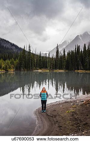 Stock Image - Portrait of woman beside lake, Kananaskis Country, Bow Valley Provincial Park, Kananaskis, Alberta, Canada. Fotosearch